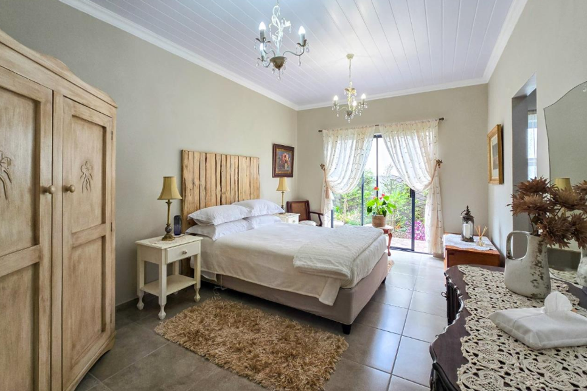 A well-maintained bedroom featuring tiled flooring, a tongue and groove ceiling, and a sliding glass door providing access to the garden.
