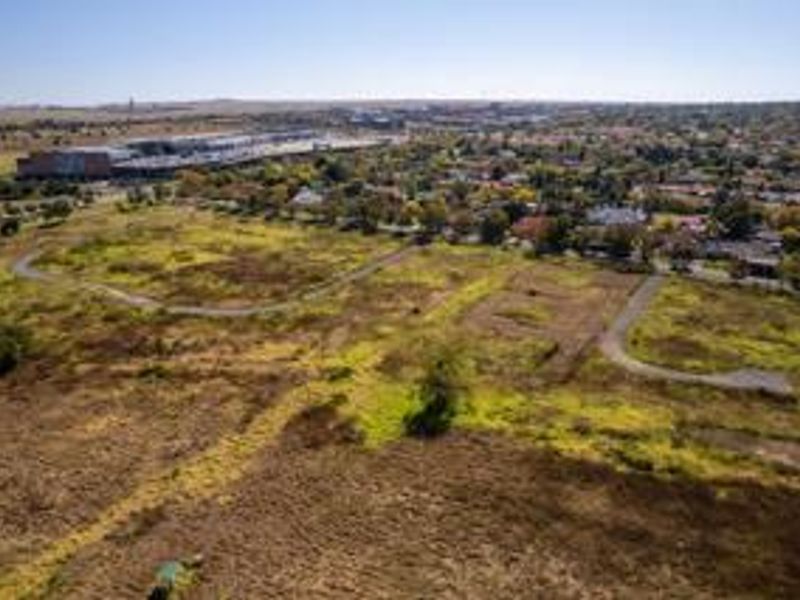 Aerial view of a large, undeveloped residential land parcel with existing paved access roads, situated near established suburban infrastructure.