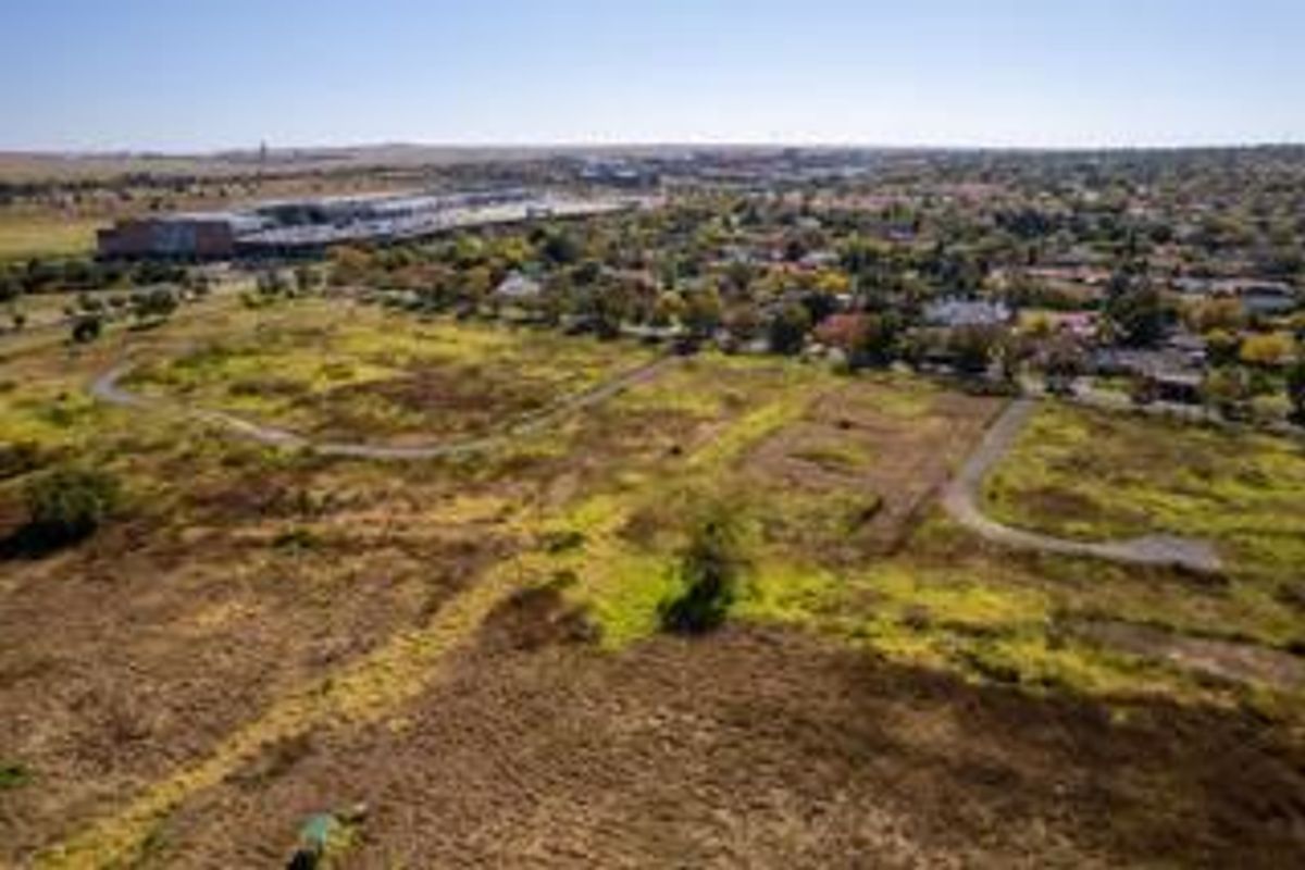 Aerial view of a large, undeveloped residential land parcel with existing paved access roads, situated near established suburban infrastructure.