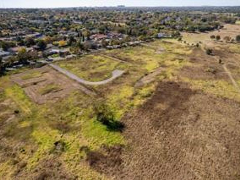 Aerial view of a large vacant residential land parcel with established road access, situated in a suburban neighborhood.