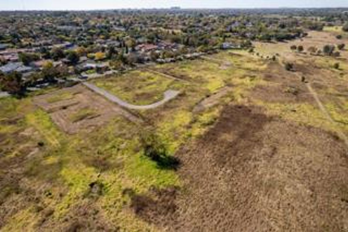 Aerial view of a large vacant residential land parcel with established road access, situated in a suburban neighborhood.