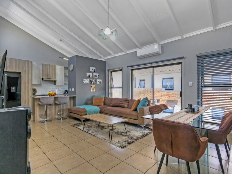 Spacious open-plan living area featuring a modern kitchen with stone countertops, vaulted ceilings, and direct access to the outdoor patio through sliding glass doors.