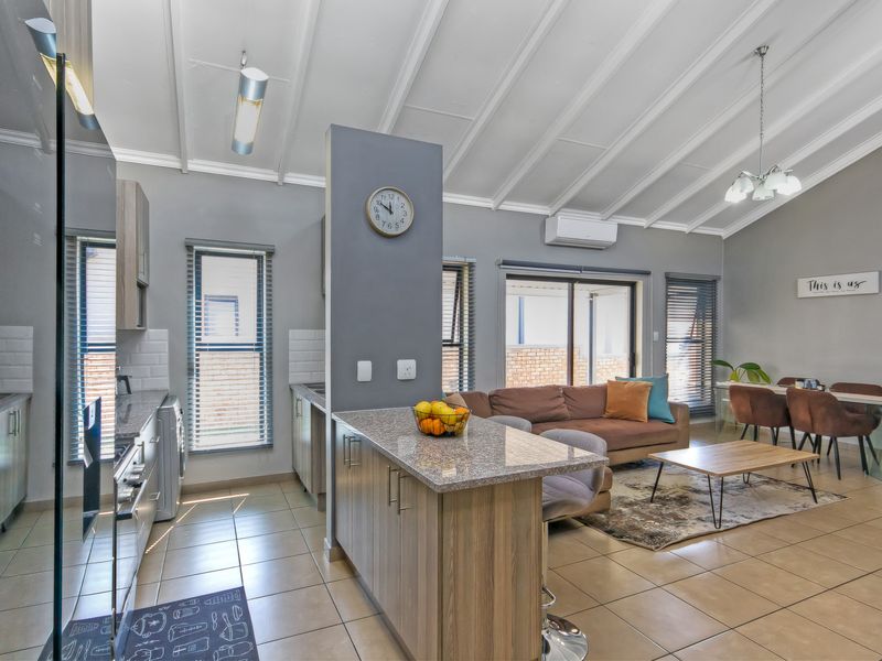 Spacious open-plan living area featuring a modern kitchen with granite countertops, vaulted ceilings, and seamless flow to the outdoor patio through sliding glass doors.