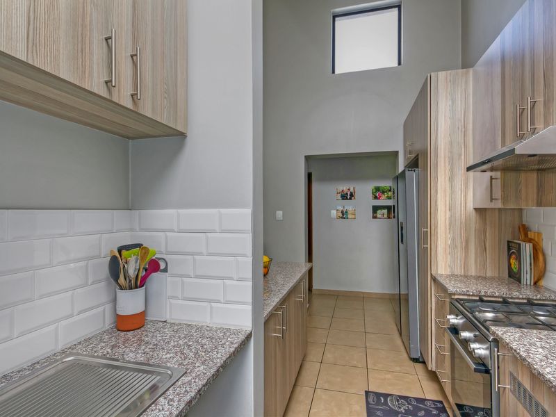 Modern kitchen featuring wood-finish cabinetry, granite countertops, subway tile backsplash, and integrated gas hob with extractor fan.