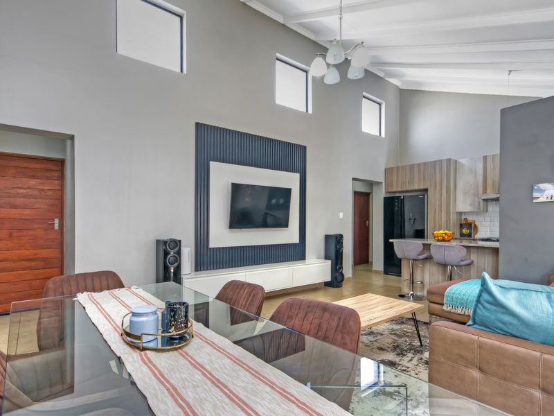 Spacious open-plan living area featuring a vaulted ceiling, modern media wall, and a functional kitchen with island seating.