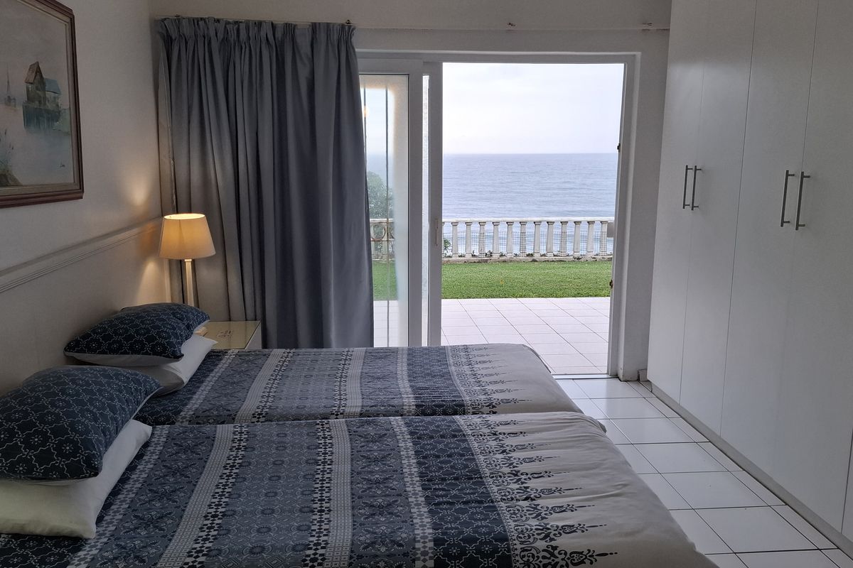 Bedroom featuring built-in cupboards, tiled flooring, and a sliding glass door opening onto a patio with ocean views.