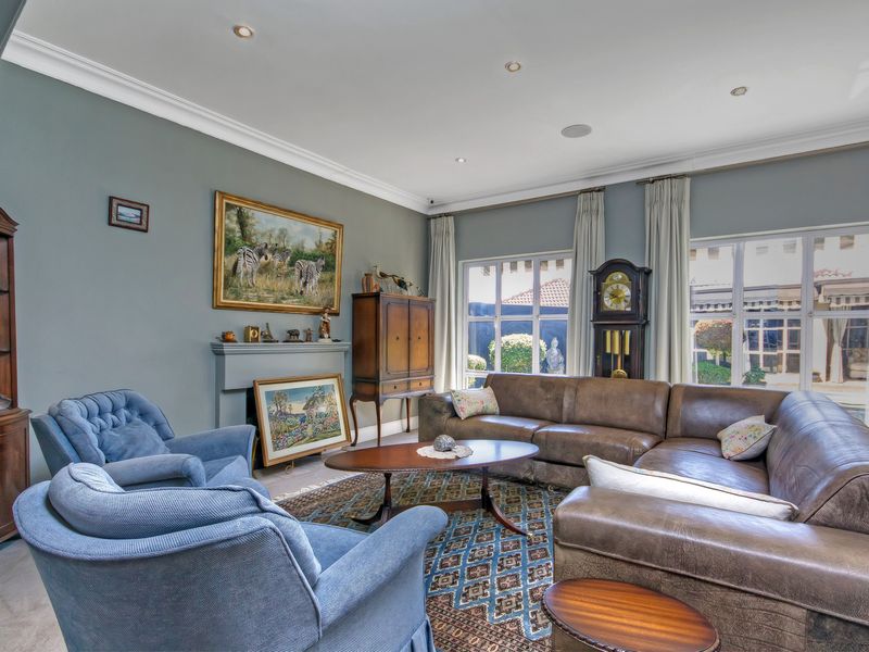 A comfortable living room featuring a fireplace mantel, recessed lighting, decorative crown molding, and large windows providing natural light.