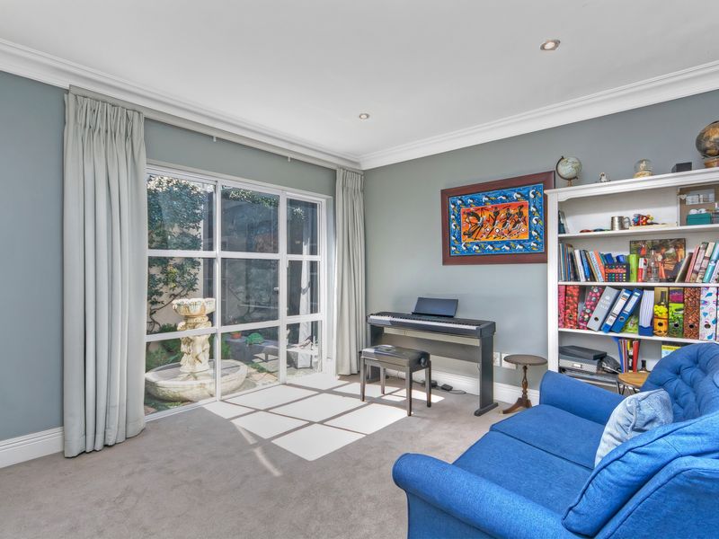 A bright living room featuring crown molding, recessed downlights, and a large glass door providing natural light and a view of the outdoor fountain.