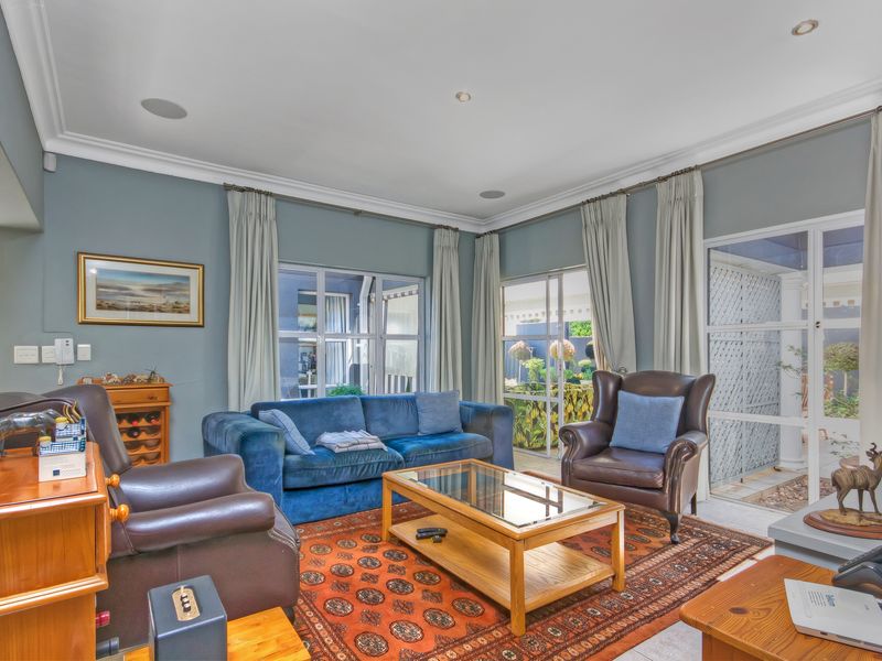 A comfortable living room featuring crown molding, recessed lighting, integrated ceiling speakers, and large glass sliding doors providing access to the outdoor area.