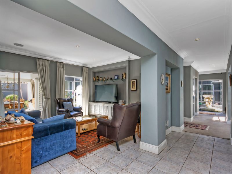 Spacious living room featuring tiled flooring, crown molding, recessed lighting, and built-in cabinetry, with seamless access to the outdoor patio area.