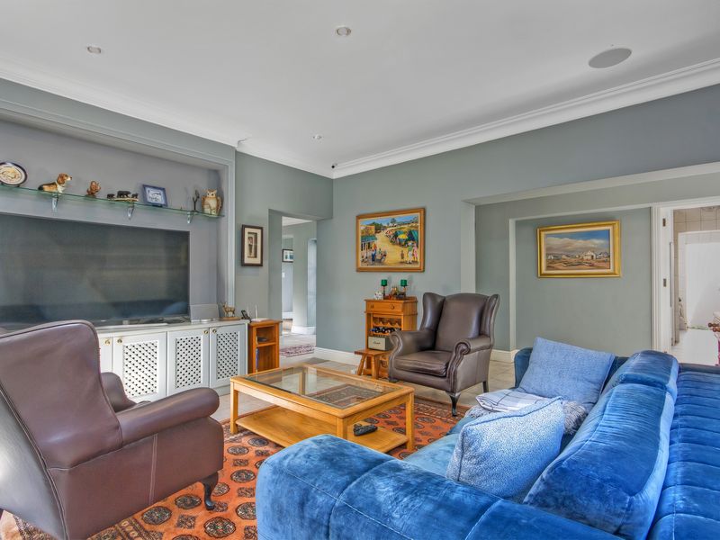 A well-maintained living room featuring built-in cabinetry, recessed lighting, and decorative ceiling coving, finished with neutral wall tones and tiled flooring.
