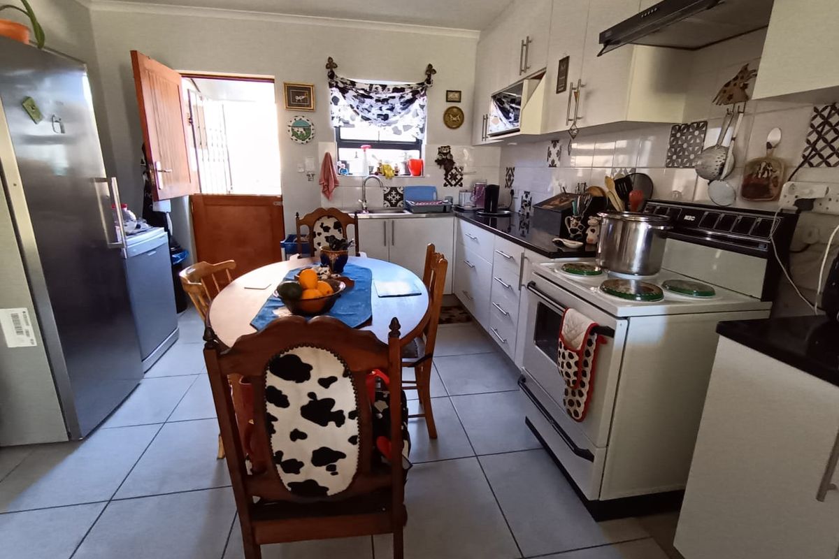 A functional kitchen featuring white cabinetry, tiled flooring, a tiled backsplash, and a freestanding stove with an extractor fan.