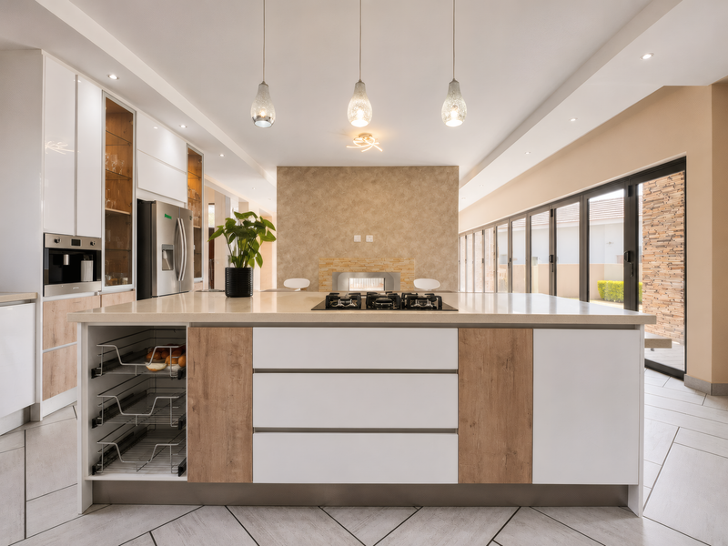 Modern kitchen featuring a large central island with integrated gas cooktop, high-end built-in appliances, and seamless access to the outdoor patio area.