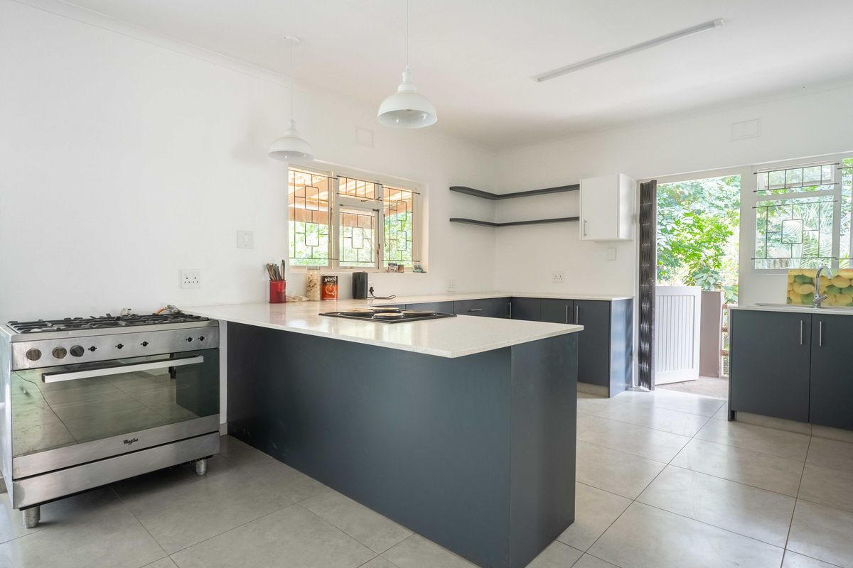 Modern kitchen featuring dark cabinetry, stone countertops, a gas stove, and direct access to the outdoor area through a security gate.