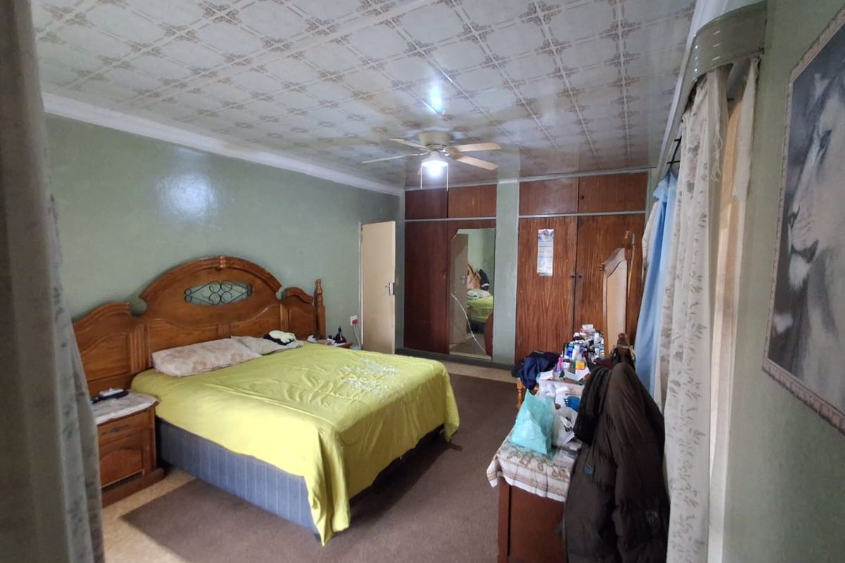 A spacious bedroom featuring built-in wooden wardrobes, a ceiling fan, and a patterned ceiling finish.