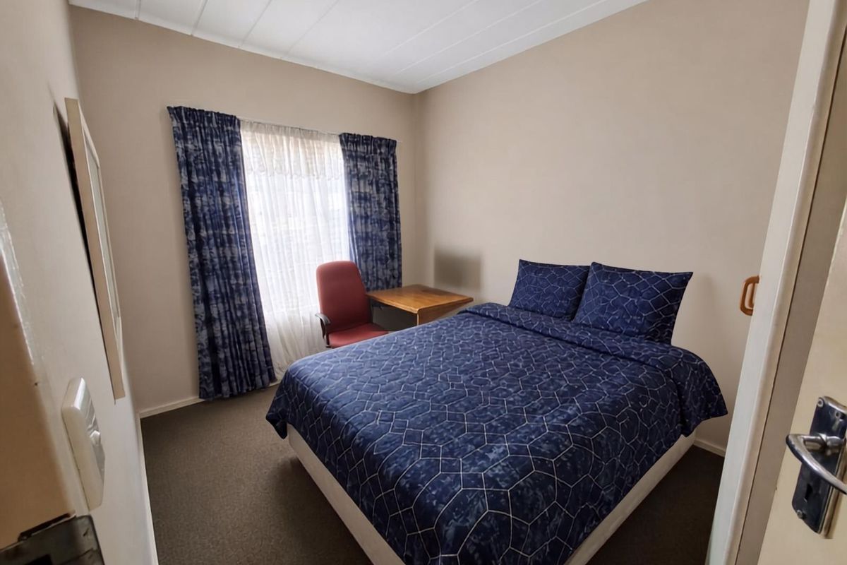 A functional bedroom featuring carpeted flooring and ceiling panels, offering a neutral base for personalization.
