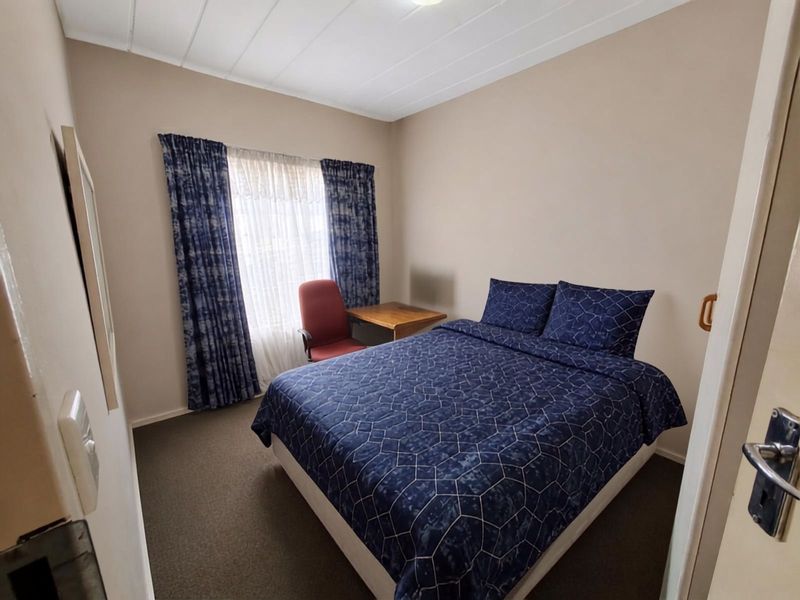 A functional bedroom featuring carpeted flooring and ceiling panels, offering a neutral base for personalization.