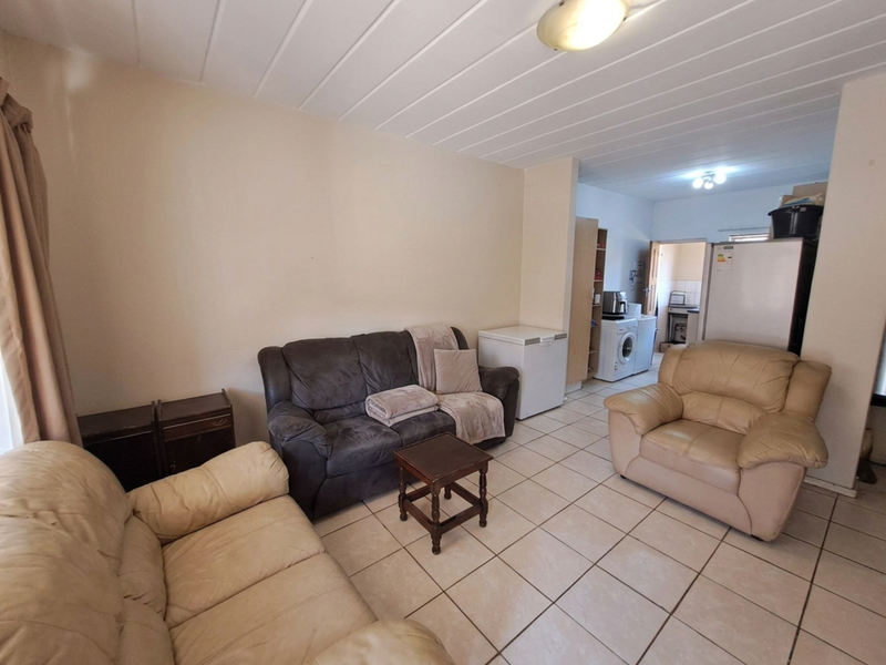 Open plan living area featuring tiled flooring and a panel ceiling, with an adjacent utility space visible in the background.