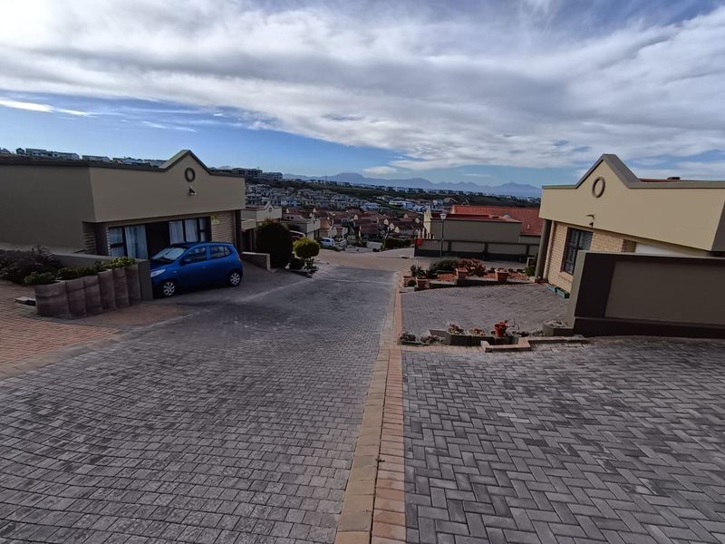 A view of the paved driveway and exterior facades of the townhouse complex, showcasing the surrounding neighborhood and mountain views.