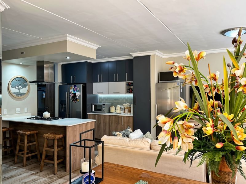 Modern open-plan living area featuring a contemporary kitchen with a central island, gas hob, sleek cabinetry, and stylish subway tile backsplash.