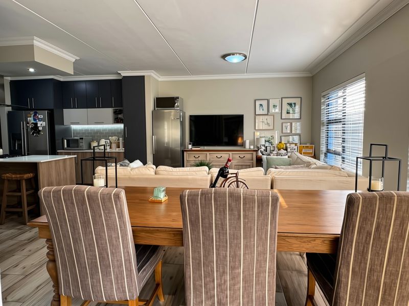 Spacious open-plan living area featuring a modern kitchen with dark cabinetry, a central island, and a seamless flow into the dining and lounge space.