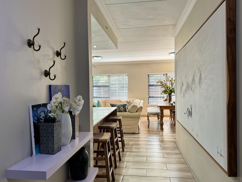 An open-plan living and dining area featuring tiled flooring, crown molding, and recessed lighting, creating a bright and cohesive living space.