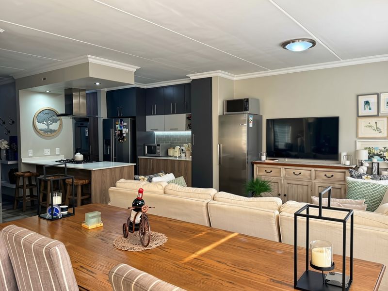 A well-maintained open-plan living and kitchen area featuring a central island, modern cabinetry, and integrated appliances, creating a functional and cohesive living space.