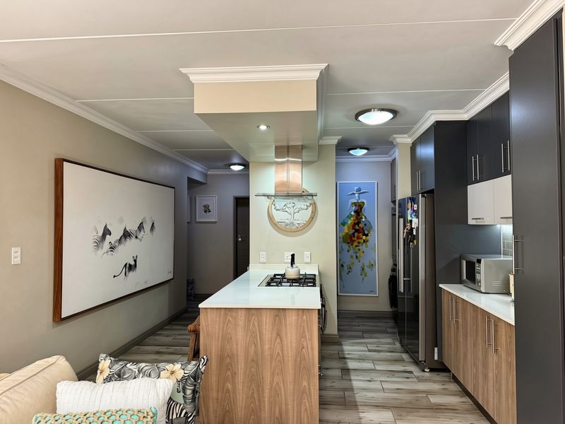 Modern kitchen featuring a central island with a gas hob, extractor fan, sleek cabinetry, and stone countertops, complemented by recessed lighting and crown molding.