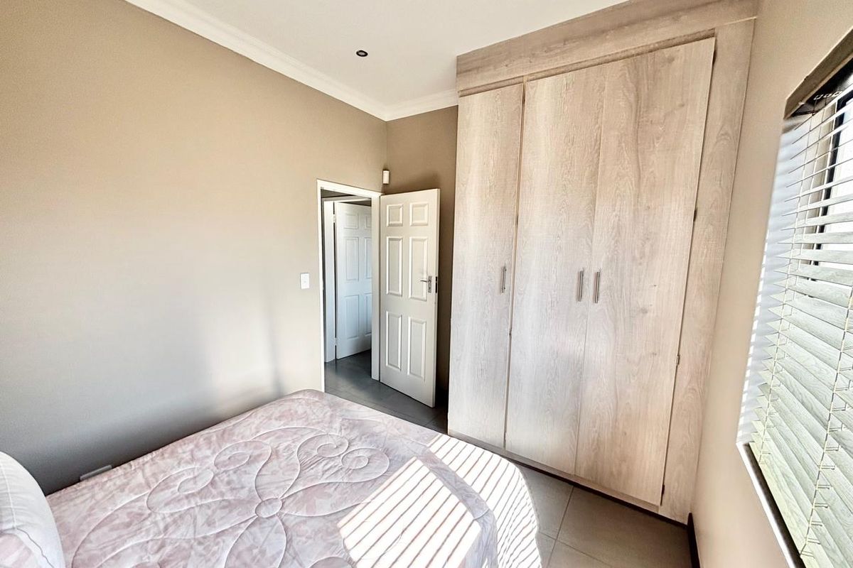 A well-maintained bedroom featuring neutral wall tones, tiled flooring, recessed lighting, and ample built-in cupboard storage.