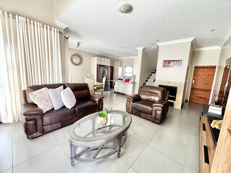 Spacious open-plan living area featuring tiled floors, a built-in fireplace with stone surround, and an integrated kitchen with cabinetry and island.