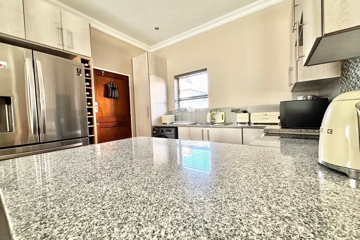 Modern kitchen featuring granite countertops, ample built-in cabinetry, a dedicated wine rack, and recessed lighting, offering a functional and well-maintained workspace.