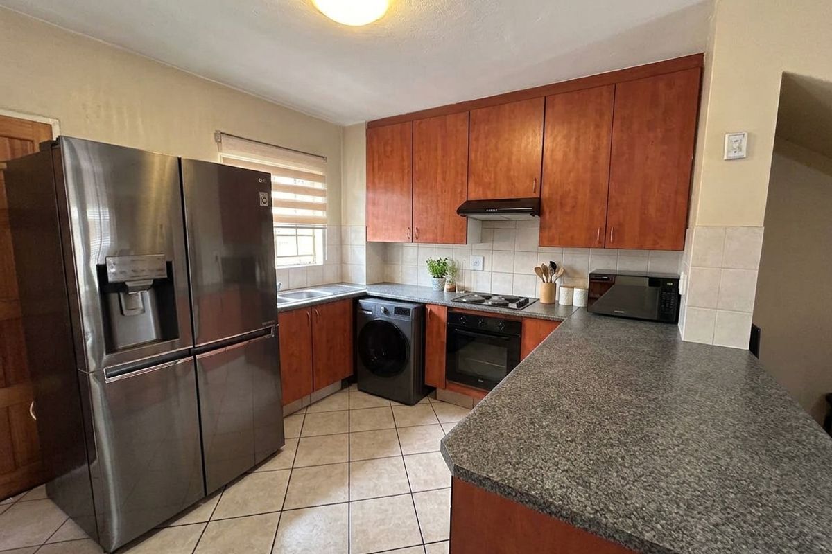 Functional kitchen featuring wood-finish cabinetry, granite-look countertops, tiled backsplash, and integrated cooking appliances with tiled flooring.