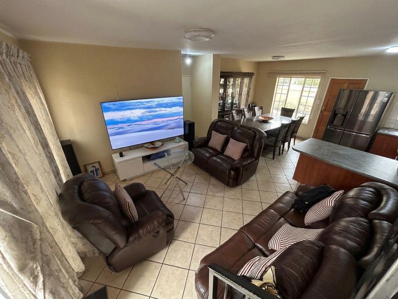 An open-plan living and dining area featuring tiled flooring, a kitchen island, and integrated cabinetry, creating a functional and connected living space.