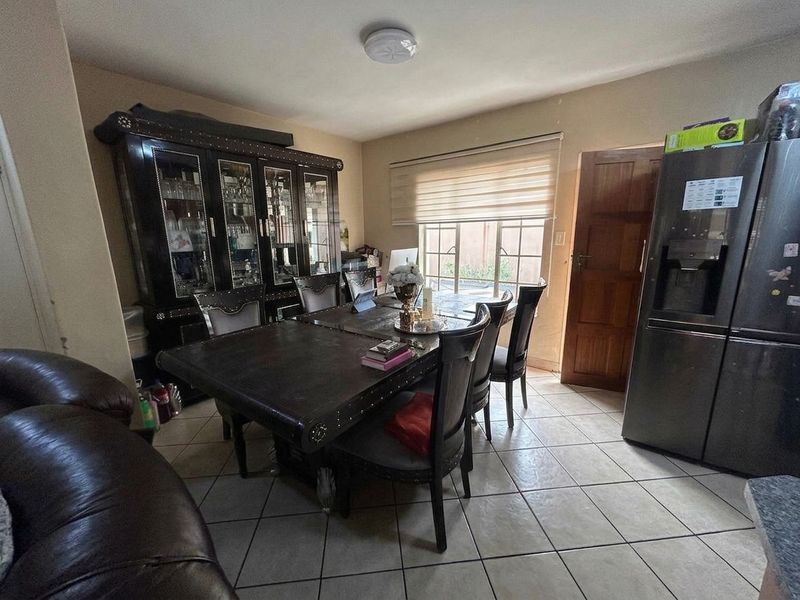 A dining area featuring tiled flooring, a flush mount ceiling light, and a window with roller blinds, providing a functional space for meals.
