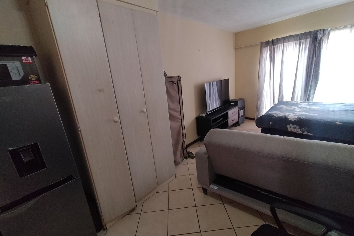 A bedroom featuring tiled flooring and a built-in wardrobe, requiring cosmetic updates to improve the overall aesthetic and condition of the space.