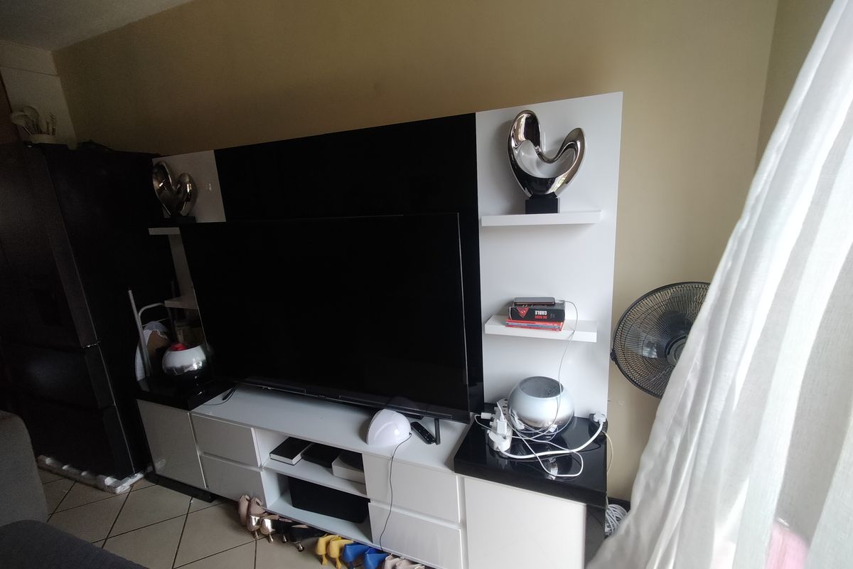 A living room featuring a modern built-in media unit with high-gloss cabinetry and ceramic floor tiles.