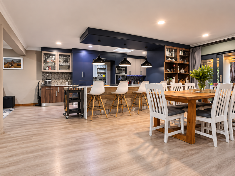 Spacious open-plan kitchen and dining area featuring modern cabinetry, a large central island with breakfast bar, and seamless access to the outdoor patio.