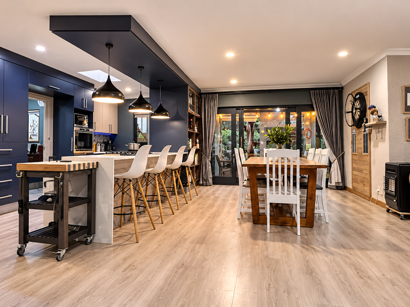 Spacious open-plan kitchen and dining area featuring modern navy cabinetry, a large central island with breakfast bar, and seamless access to the outdoor patio.