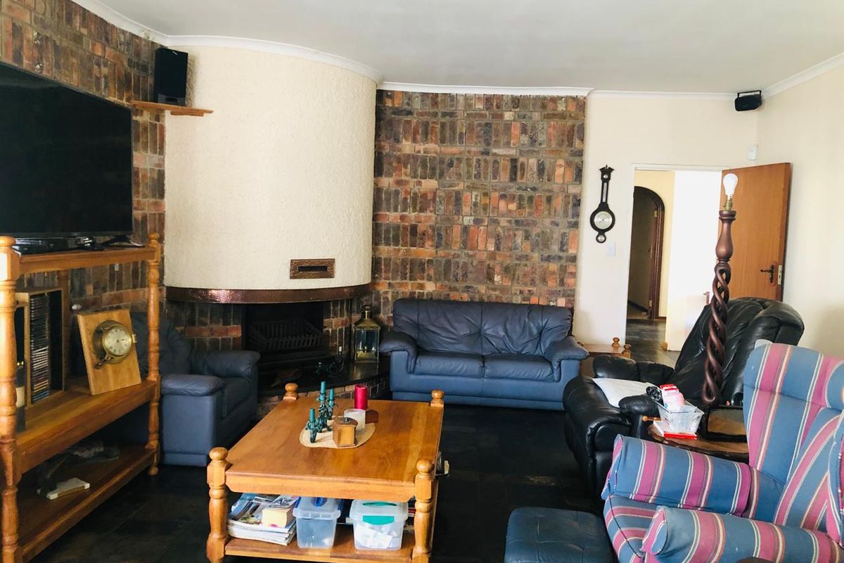 Living room featuring a prominent brick fireplace with a curved hearth and dark slate flooring.