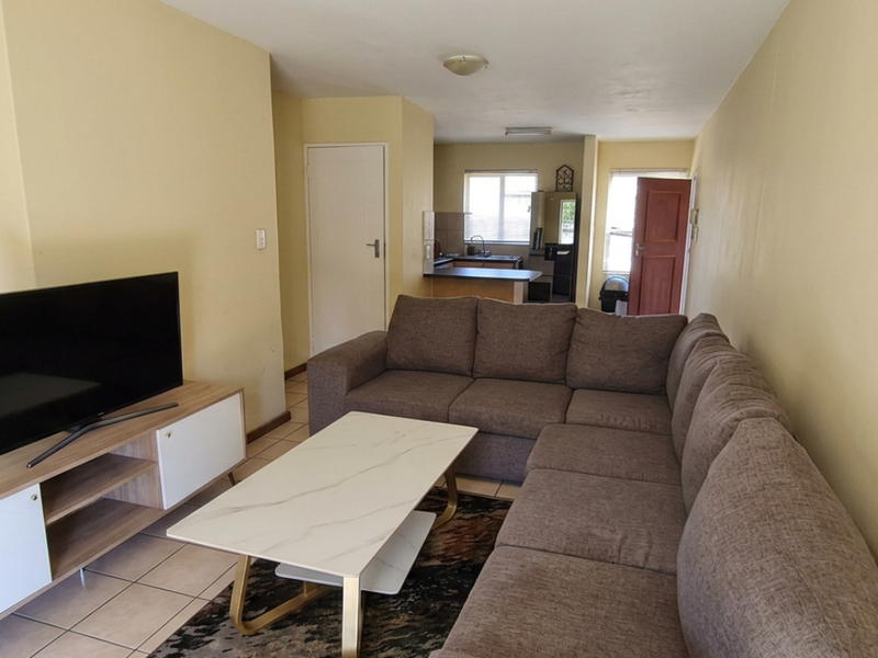 Open plan living area featuring tiled flooring and a connected kitchen space, offering a functional layout for daily living.