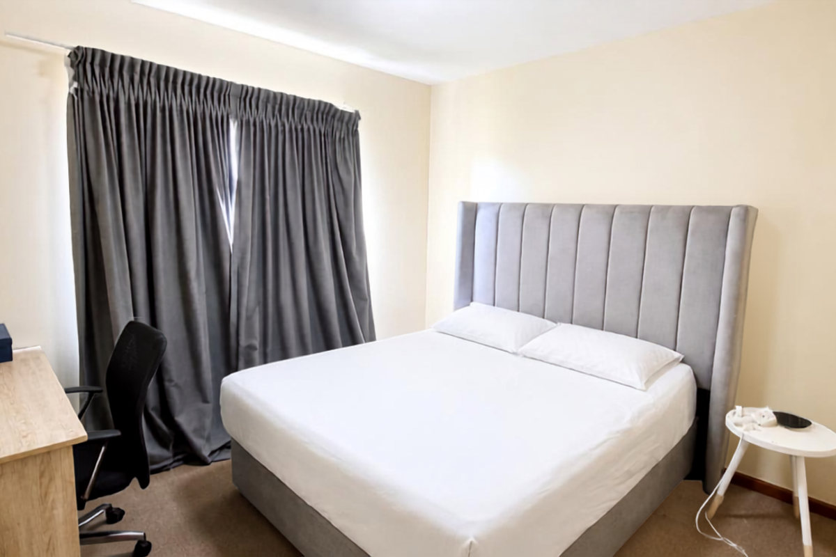 A functional bedroom featuring neutral wall finishes, carpeted flooring, and a curtain track for window treatments.