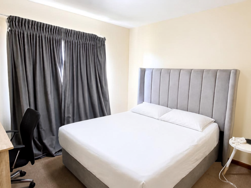 A functional bedroom featuring neutral wall finishes, carpeted flooring, and a curtain track for window treatments.