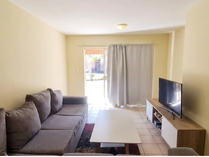 A functional living room featuring tiled flooring and a sliding glass door providing access to the exterior.