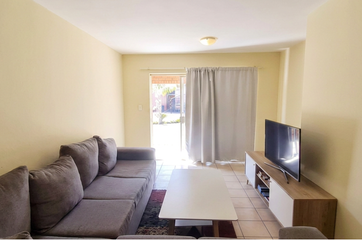 A functional living room featuring tiled flooring and a sliding glass door providing access to the exterior.