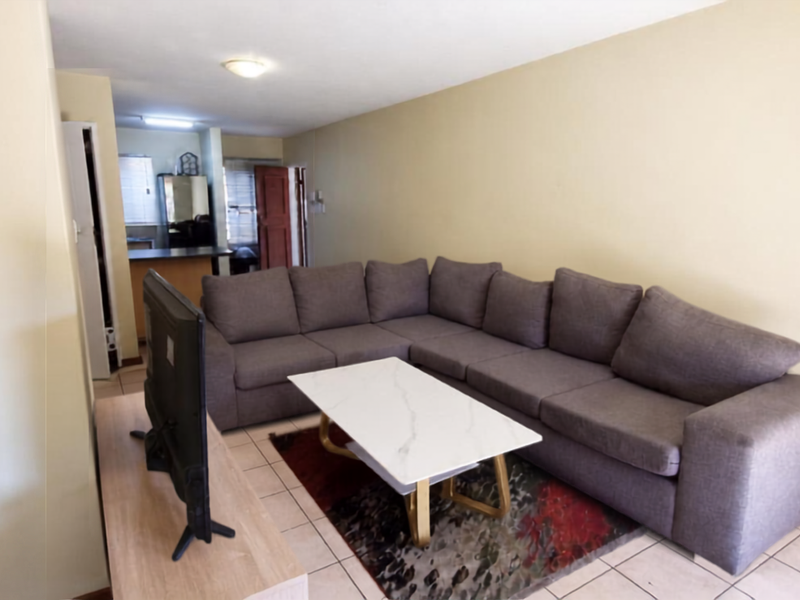 Open plan living area featuring tiled flooring and neutral wall finishes, with a view through to the kitchen area.