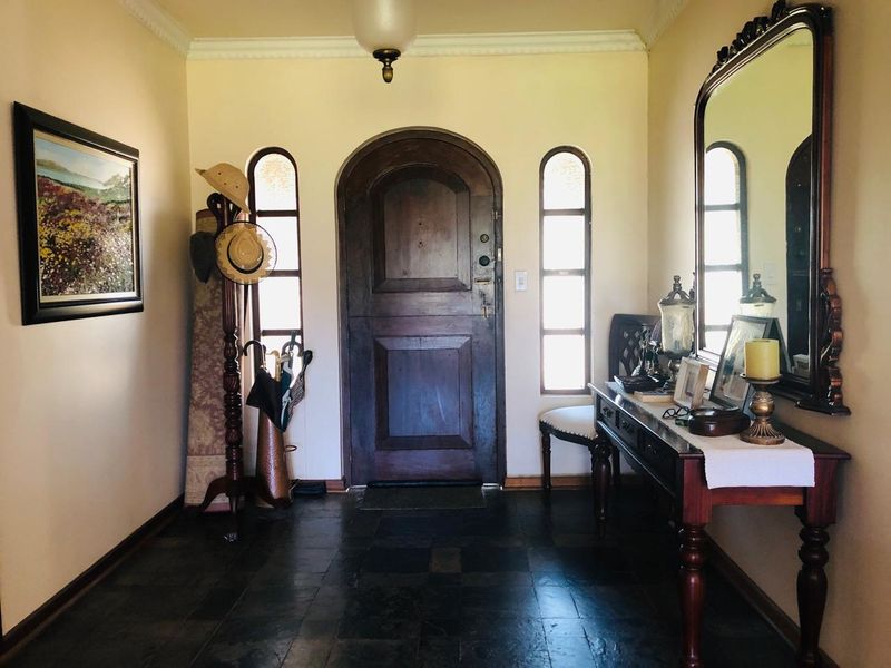 A welcoming entrance hall featuring a solid timber arched front door, flanked by vertical side windows and finished with dark slate floor tiles.