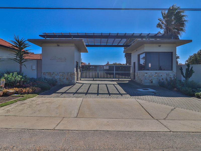 The main entrance gate to the estate features a modern security guardhouse, stone cladding accents, and a pergola structure over the driveway.