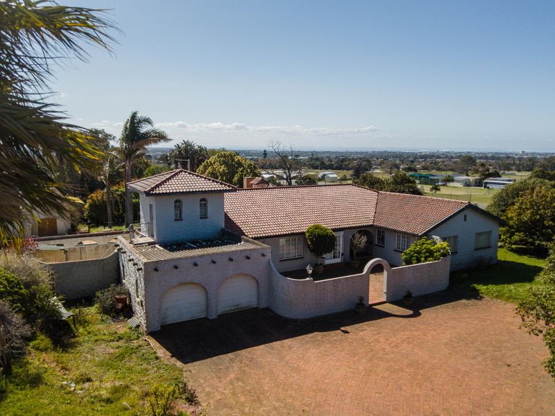 Aerial view of a Mediterranean-style house featuring a tiled roof, double garage, and a walled courtyard entrance set on a spacious property.
