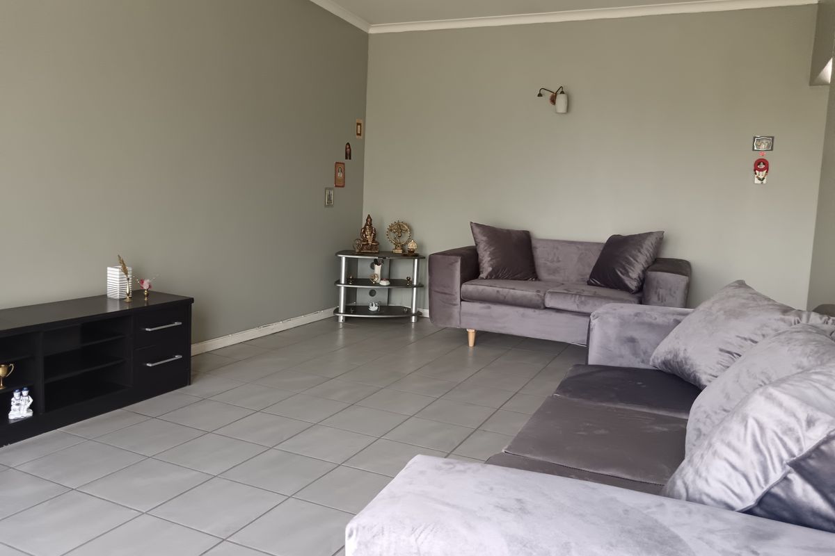 A spacious living room featuring neutral grey walls, tiled flooring, and a coved ceiling, providing a clean and functional base for interior design.