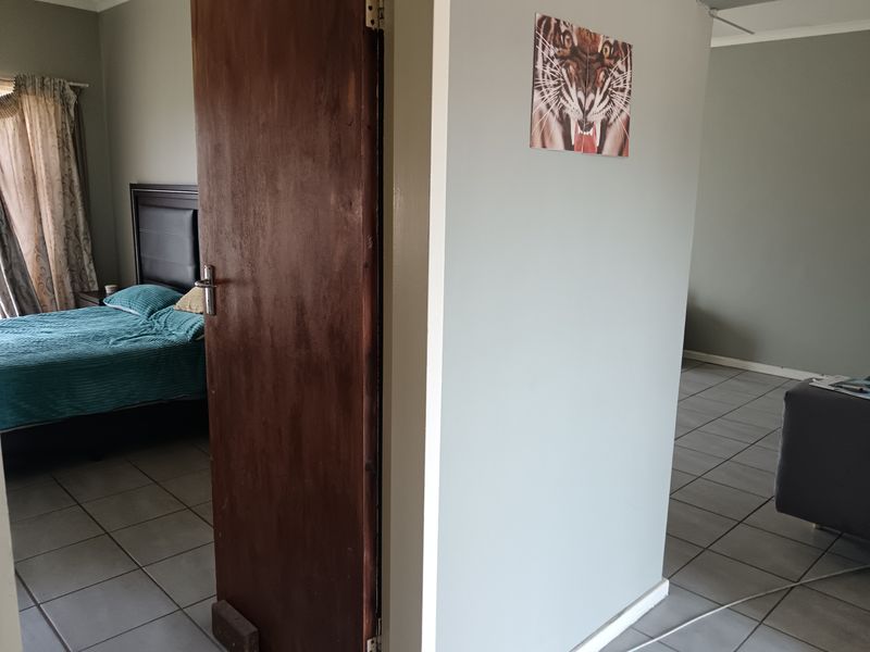 A bedroom interior featuring tiled flooring and a wooden door, showing standard residential finishes and layout.
